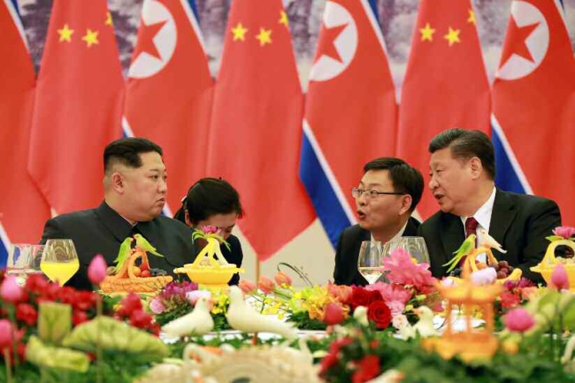 North Korean leader Kim Jong-un, left, is seen talking with Chinese President Xi Jinping on March 28. (Yonhap)