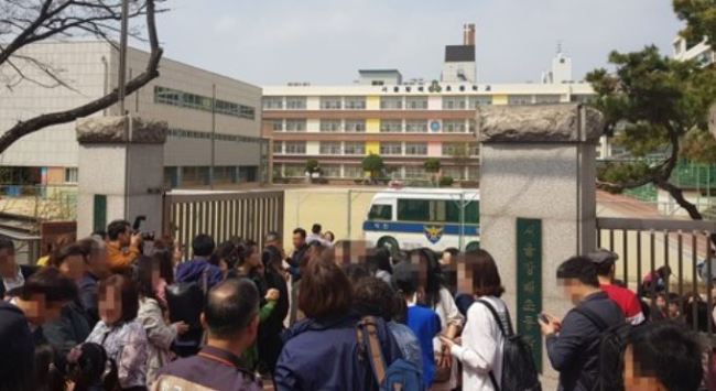 The front gate of the Bangbae Elementary School is crowded with police authorities and parents after a man took a female student hostage for about an hour before being subdued by police on April 2. (Yonhap)