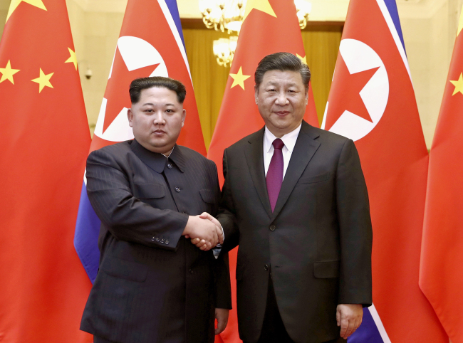 In this file photo provided Wednesday, March 28, by China`s Xinhua News Agency, North Korean leader Kim Jong Un, left, and Chinese President Xi Jinping shake hands in Beijing. (Yonhap-AP-Xinhua)