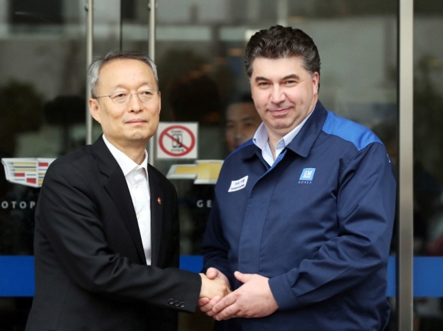 Paik Un-gyu, minister of trade, industry and energy, and Berry Engle, head of GM International, shake hands in front of GM Korea’s Bupyeong plant on April 6. (Yonhap)