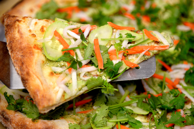 Slice`s banh mi pizza pairs cheese and lemongrass-infused pork sausage with a piquant, cliantro-based sauce, cucumber, pickled carrots and daikon radish. Park Hyun-koo/The Korea Herald