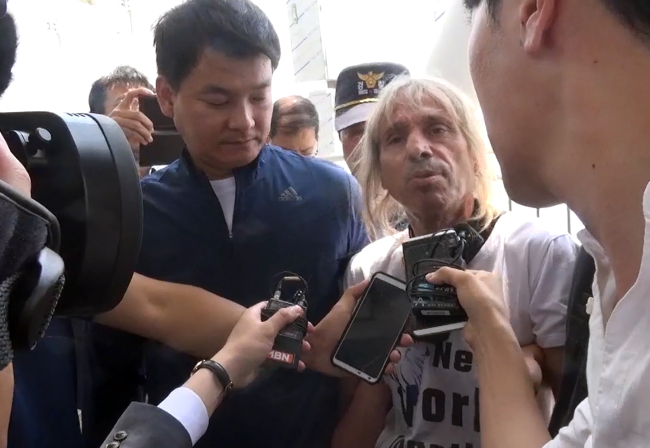 Alain Robert speaks to Korean reporters at the scene of his arrest. (Yonhap)