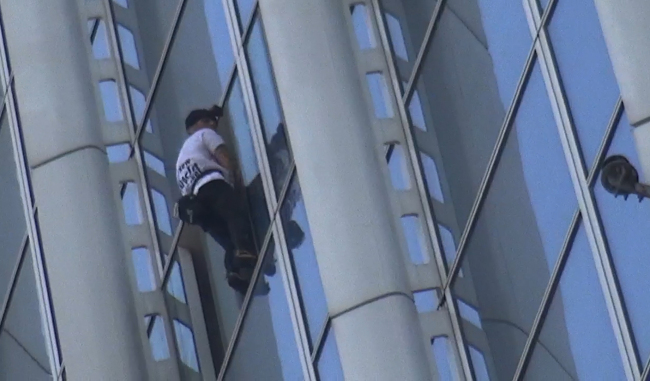Alain Robert was seen scaling the facade of the tallest building in Korea without safety gears. (Yonhap)
