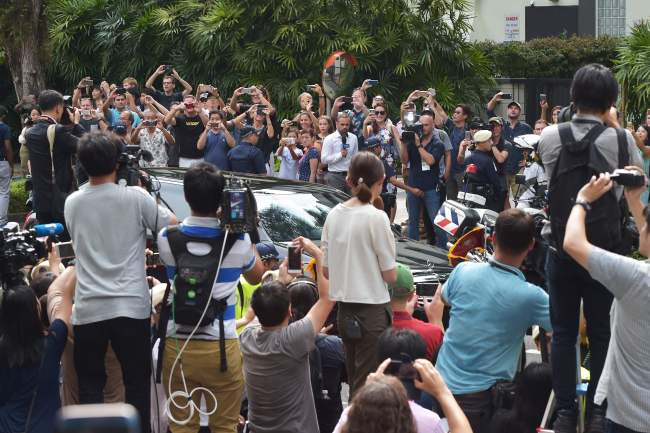 Journalists and onlookers watch the motorcade carrying North Koran leader Kim Jong-un (not pictured) arriving at the St. Regis hotel. (AFP-Yonhap)
