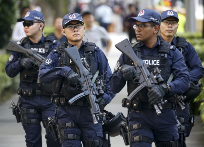 Singaporean security personnel stand guard near the the St Regis hotel, where North Korean leader Kim Jong-un is staying in Singapore, on Monday. (EPA-Yonhap)