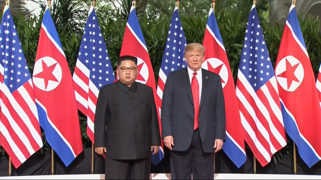In this image made from video provided by Host Broadcaster Mediacorp Pte Ltd., US President Donald Trump and North Korean leader Kim Jong-un pose together ahead of their meeting at Capella Hotel in Singapore, Tuesday. (AP-Yonhap)