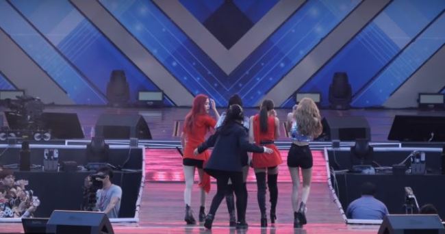 Black Pink are sent off stage by a staff member during their performance of 