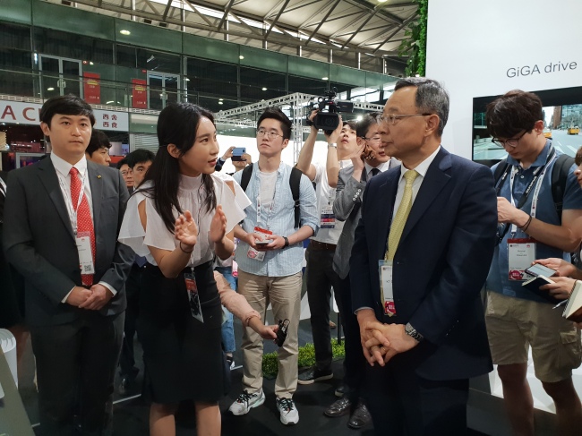 KT Chairman Hwang Chang-gyu (right) listens to a presentation at the KT booth set up at Mobile World Congress Shanghai 2018 that opened Wednesday. (By Song Su-hyun/The Korea Herald)