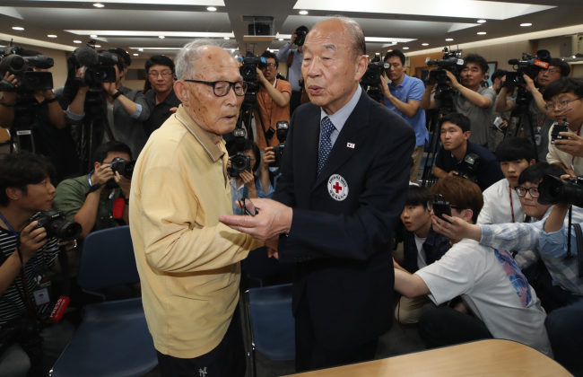 A family reunion candidate (left) holds hands with Korean Red Cross chief Park Kyung-seo at a meeting in Seoul on Monday (Yonhap)