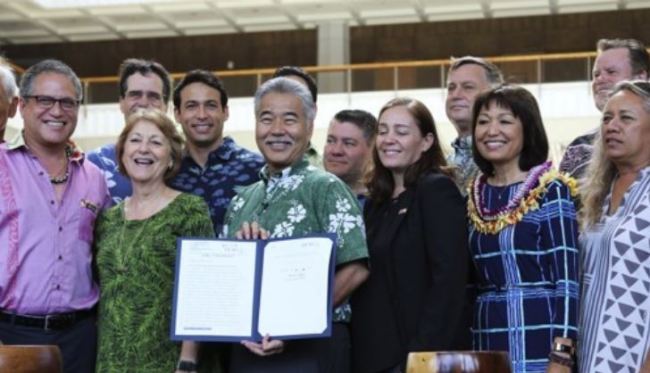 3일(현지시간) 미국 하와이 주 해변에서 유해 화학성분이 들어간 자외선 차단제를 사용하지 못하도록 하는 법안에 서명한 데이비드 이게 하와이 주 지사(가운데) (AP=연합뉴스)