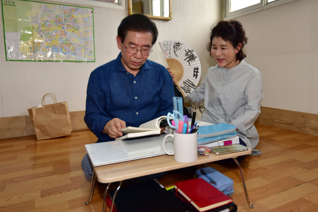 Seoul Mayor Park Won-soon (left) reads at his new, temporary residence -- a rooftop dwelling in Samyang-dong of Gangbuk-gu district of Seoul -- along with his wife, Kang Nan-hee (right).