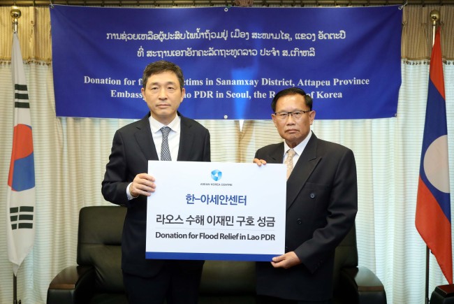 Secretary-General Lee Hyuk (left) delivers a donation to Laos Ambassador to Korea Khamsouay Keodalavong at the Laos Embassy in Seoul on Aug. 6. (ASEAN-Korea Center)