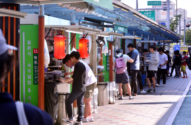 Test-takers and tourists eat quick meals in Noryangjin Cup Rice Alley (Park Hyun-koo / The Korea Herald)