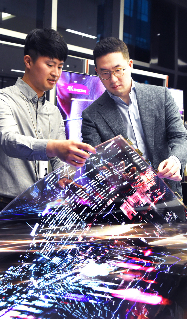 LG Chairman Koo Kwang-mo looks at a transparent flexible organic light-emitting diode display at LG Science Park in Magok, western Seoul, Wednesday. (LG Corp.)