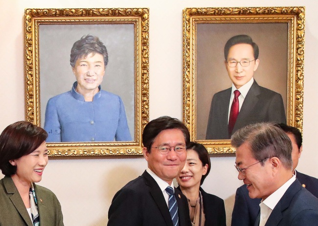 Ex-president Lee Myung-bak`s portrait (right in the back) is hung on the wall of Cheong Wa Dae. In the photo, current President Moon Jae-in (far right) is speaking to Education Minister Yoo Eun-hae (far left) on Oct. 8. (Yonhap)
