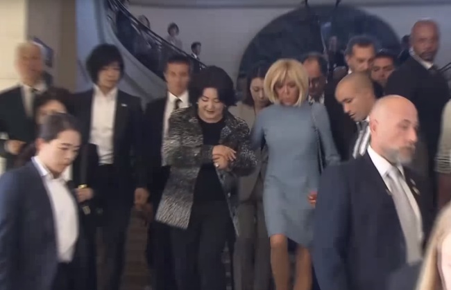 Photo caption: First ladies Kim Jung-sook (left) and Brigitte Macron descend the stairs with their arms locked at the Louvre Museum. (Yonhap)