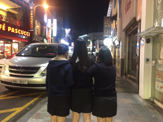 High school students Yoo Jin-ah (far left), Kang Eun-ji (middle) and Kim Yoon-seo (far right) pose for a photo in their uniforms after an interview with The Korea Herald on Oct. 4. The names have been changed at their request. (Claire Lee/ The Korea Herald)