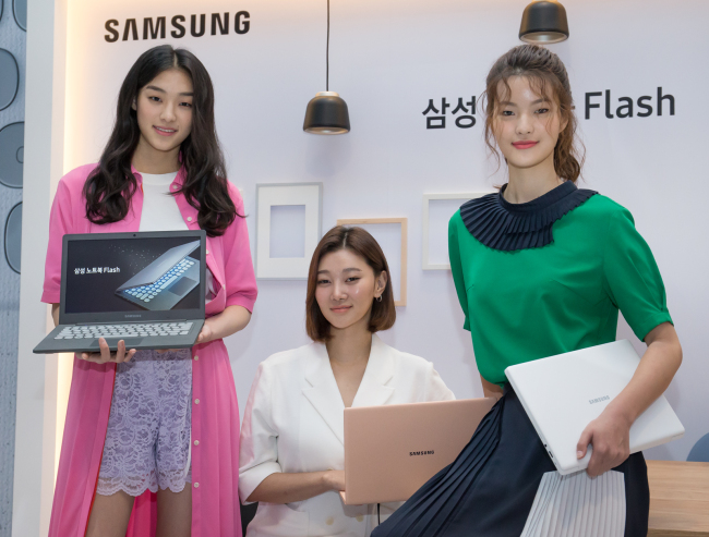Models showcase Samsung Electronics’ new laptop “Flash” with a fast internet speed and a retro-style keyboard at an event held at Pier59 Studios in Seoul on Monday. (Samsung Electronics)