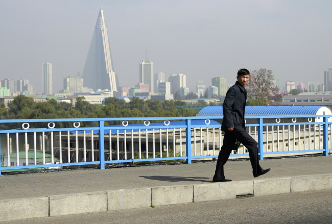 A man walks on a bridge as the city skyline with pyramid-shaped Ryugyong Hotel is seen in the background in Pyongyang, North Korea, Sunday. (AP)