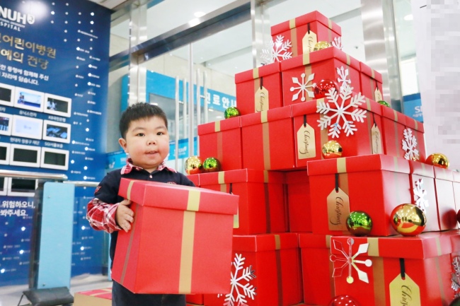 WISH TREE -- A child stands next to a wish tree set up by Hanwha Galleria and the Make-A-Wish Korea foundation at Seoul National University Children’s Hospital in central Seoul, Tuesday. The Christmas event, the first of its kind to be organized by the company, is intended to help children under treatment to celebrate the holiday season by offering gifts to those participating, according to Hanwha Galleria. (Yonhap)