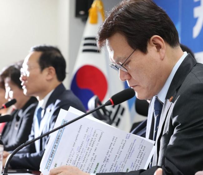 Choi Jong-ku, head of the Financial Service Commission, looks over prepared materials before a government-ruling party meeting on Nov. 26, 2018, at the National Assembly in Seoul to discuss lowering credit card commissions for small merchants. (Yonhap)