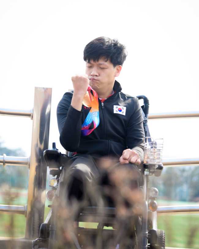 Korean national boccia player Jeong Ho-won clutches his medal Thursday while shooting the documentary film “Boccia” in Incheon.
