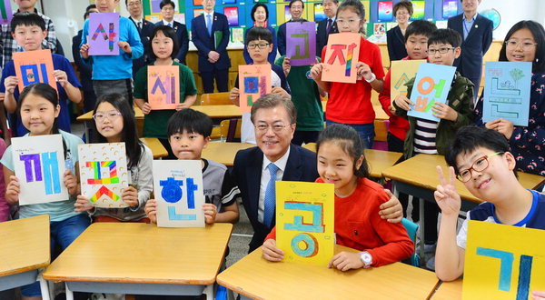 President Moon Jae-in (center) poses for a photo with elementary schoolchildren holding signs that together read 