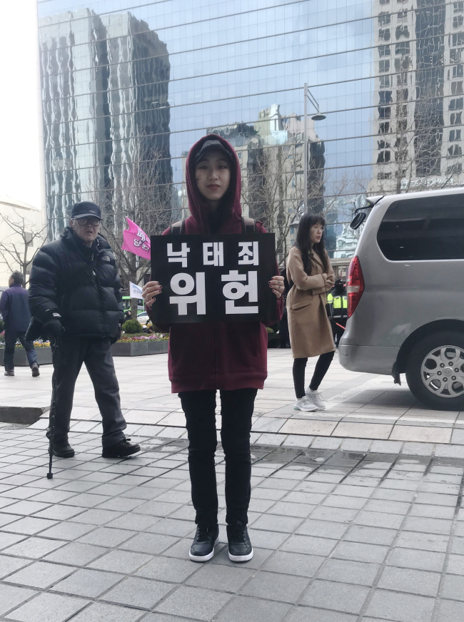 Hong Seung-hee holds a placard that reads “Criminalizing abortion unconstitutional” at a rally against a ban on abortion, in central Seoul, Saturday. (Hong Seung-hee)