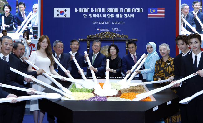 President Moon Jae-in (center left) and first lady Kim Jung-sook (center right) make bibimbap, a Korean dish of rice mixed with vegetables, at the K-Wave & Halal Show on March 12. They are joined by Malaysian and Korean businessmen along with Korean celebrities. (Yonhap)