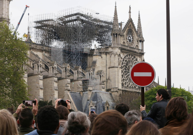 People crowd at the road in front of the Notre Dame Cathedral after a fire in Paris, France, on April 16, 2019. (Yonhap)