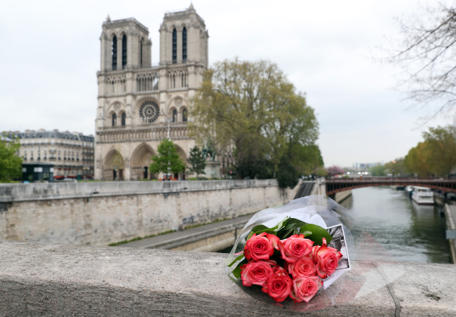 Flowers are laid before Notre Dame Cathedral after a giant fire was put down in Paris 16 April 2019. French President Emmanuel Macron vowed to rebuild the 13th century building that welcomes tens of millions of worshippers and tourists per year. (Yonhap)