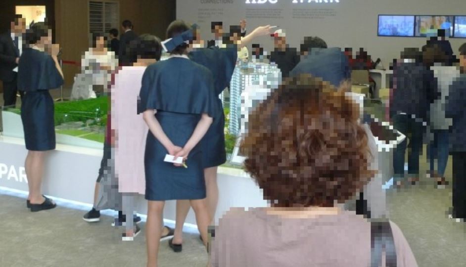 Members of the public observe a model house, which showcases miniature exteriors and actual-size interiors for an apartment complex, in a satellite city in Gyeonggi Province. (HDC Group)