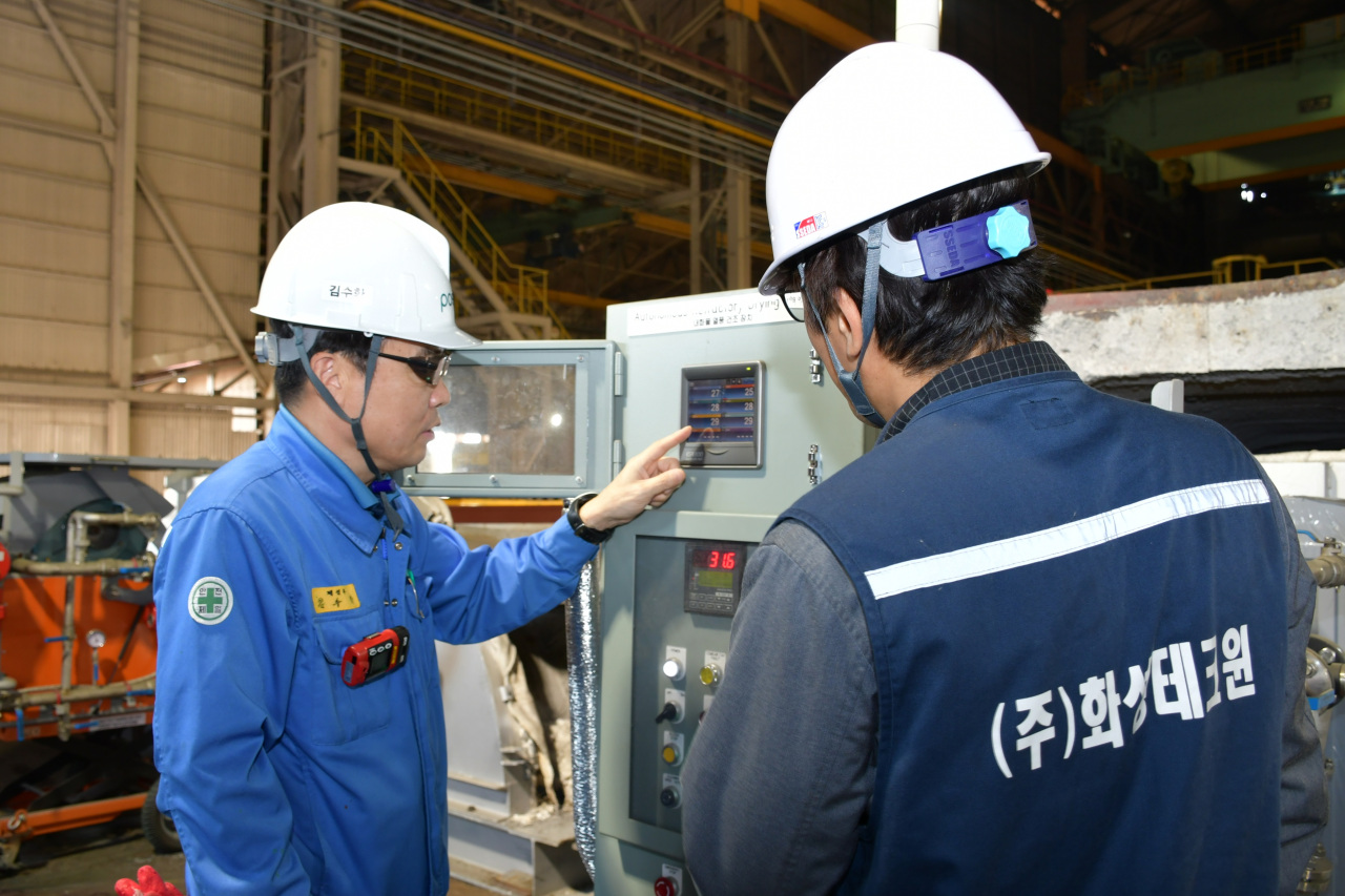 Employees of Posco and partner firm Hwa Sung Tech Win survey a sealed hot air drying facility. (Posco)