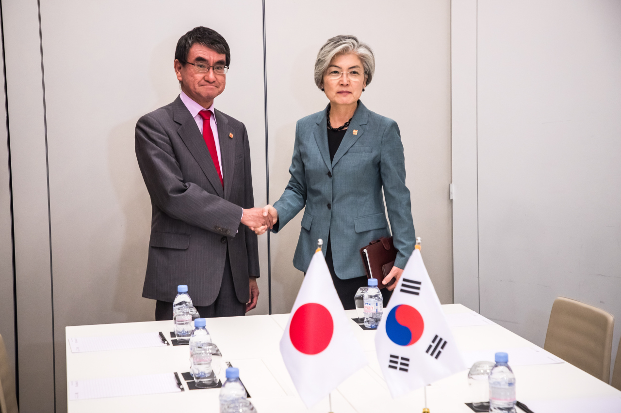 South Korean Foreign Minister Kang Kyung-wha (right) and Japanese Foreign Minister Taro Kono shake hands during the Organization for Economic Cooperation and Development ministerial council meeting in Paris on May 23. (Yonhap)