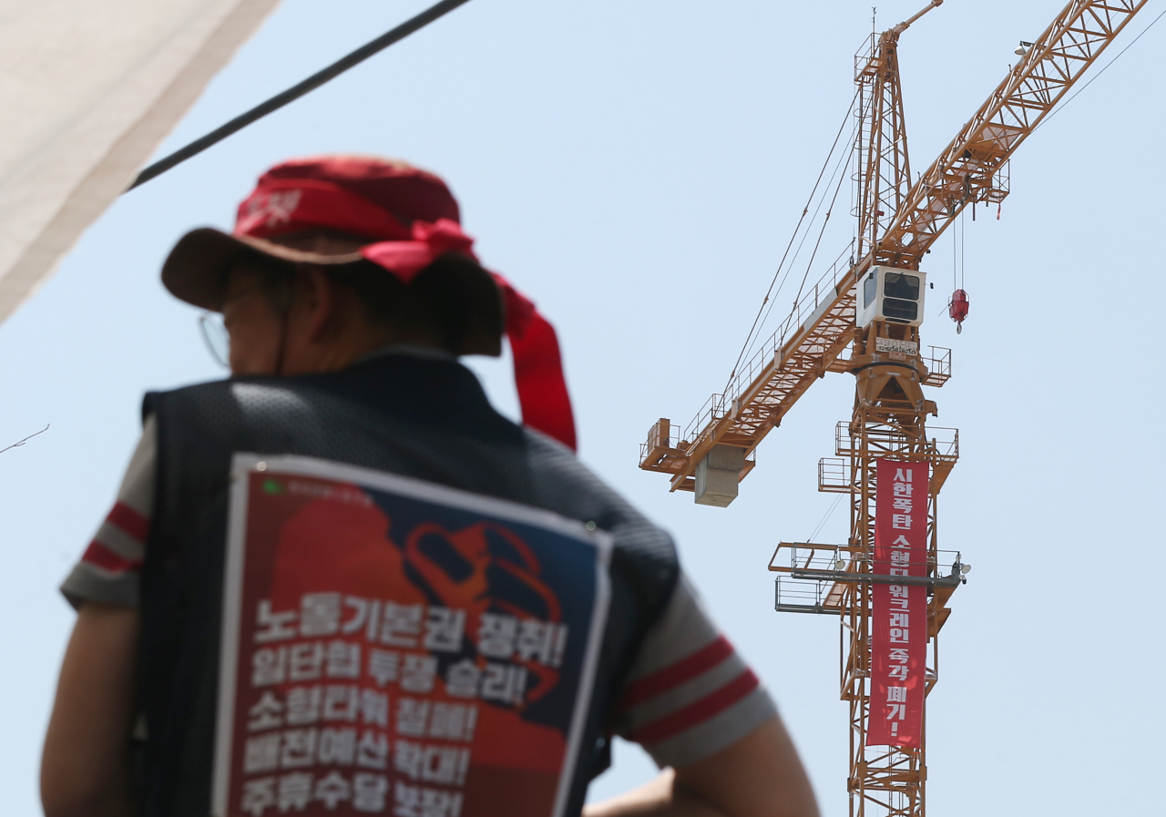 Striking tower crane workers stage a sit-in to protest the use of small tower cranes at an apartment construction site in Ulsan on Tuesday. (Yonhap)