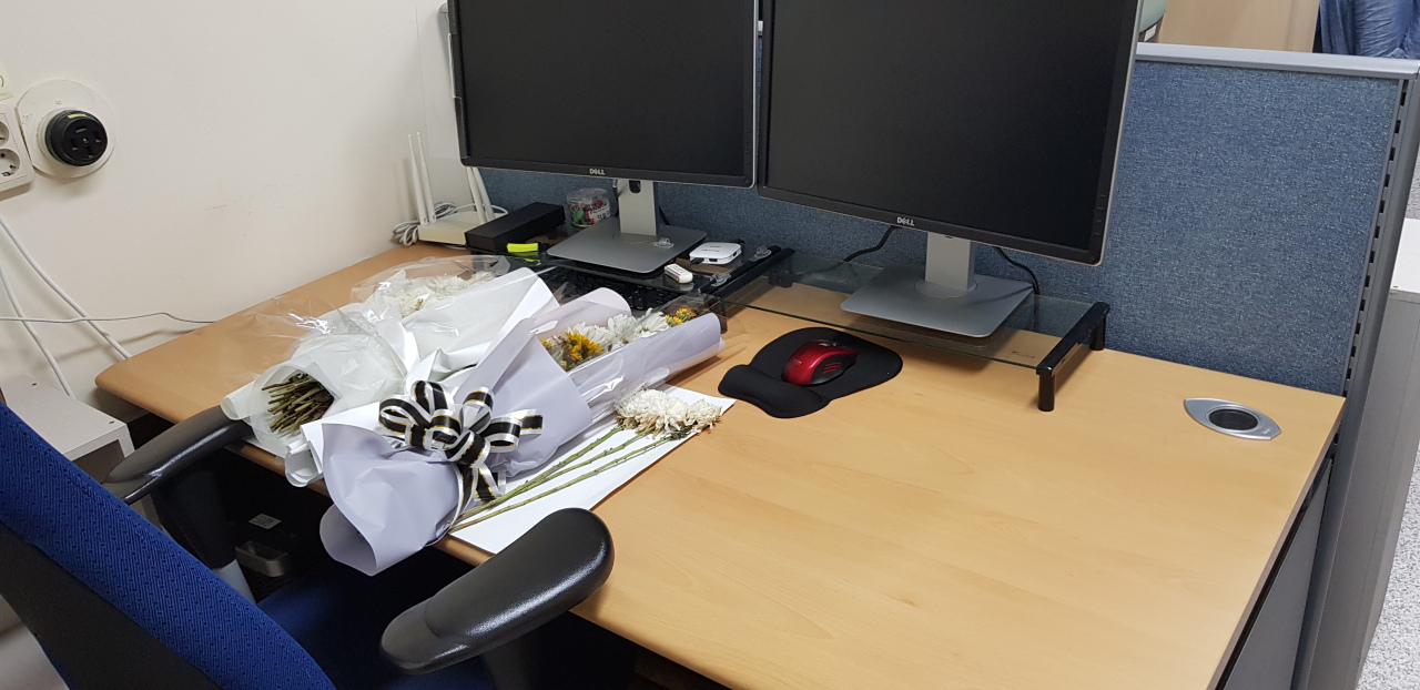 White flowers of mourning are placed on the desk that belonged to the victim in the lab where he studied. (Photo provided by a teaching assistant at university where Kang was graduate student.)