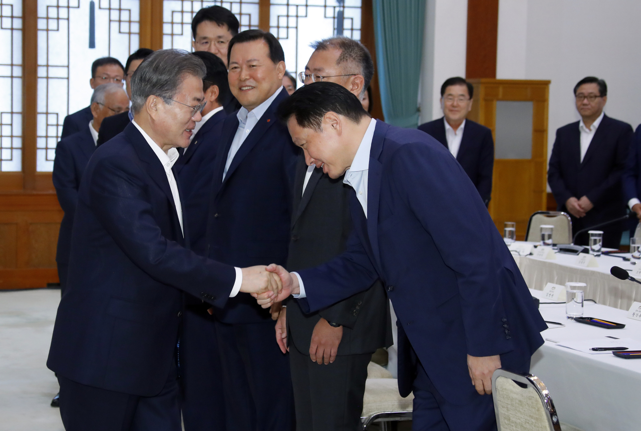 President Moon Jae-in (left) shakes hand with SK Group Chairman Chey Tae-won before a group meeting with 30 South Korean conglomerates to discuss Japan’s export restrictions. (Yonhap)