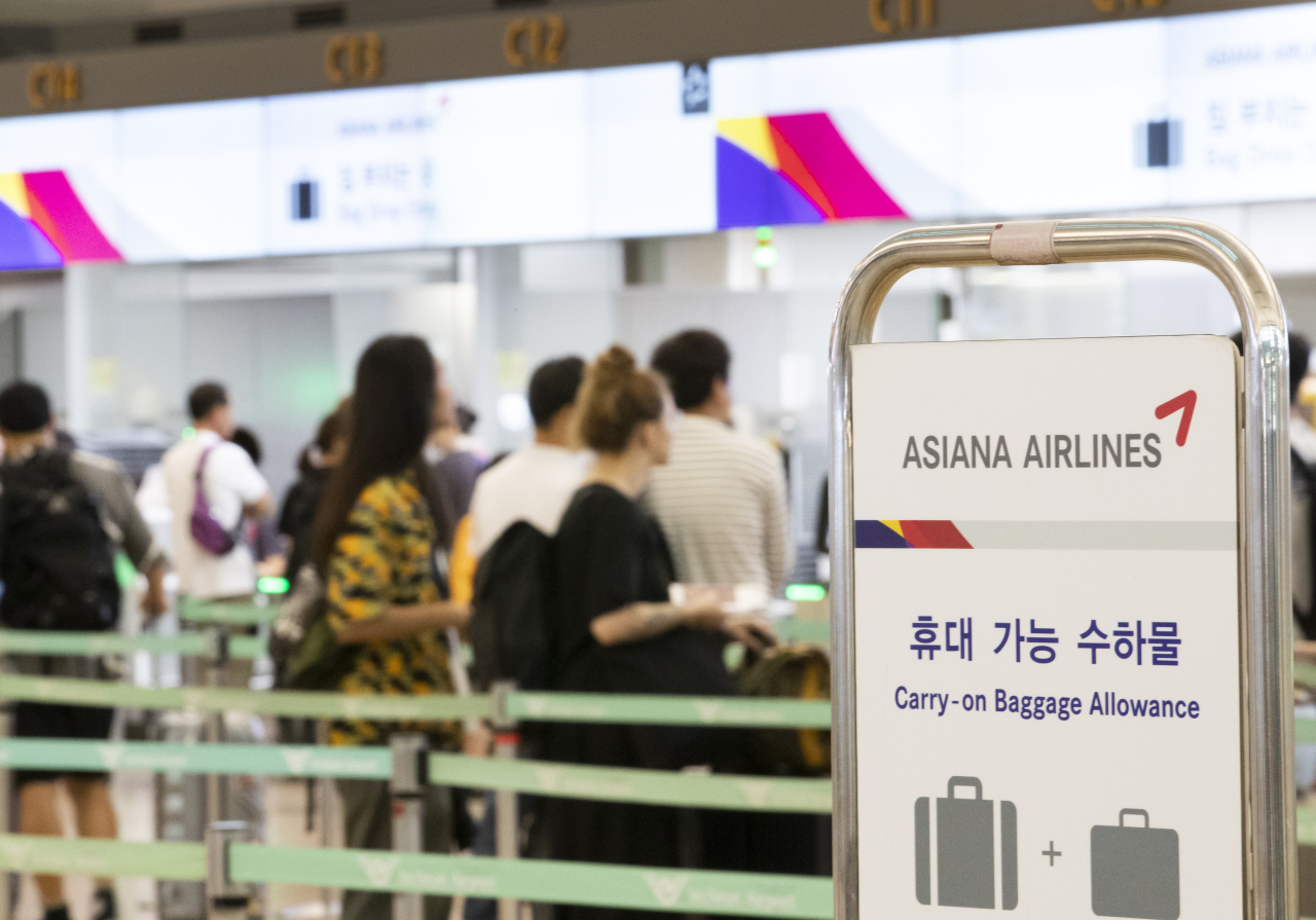 Japan-bound travelers wait in line at Asiana Airlines’ counter at Incheon Airport on Wednesday. (Yonhap)