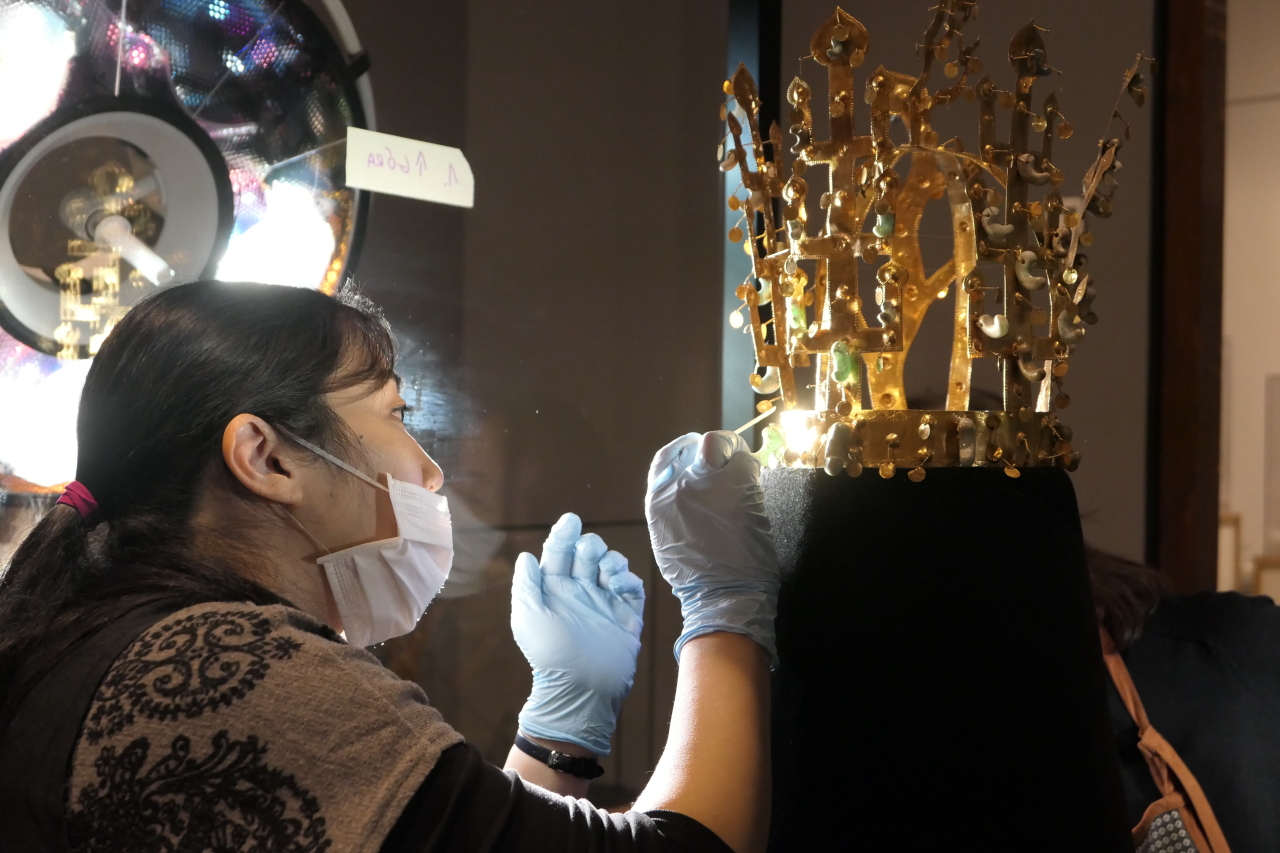 Curator Yang Seung-mee sets up a sixth-century gold crown from the Silla Kingdom at the National Museum in Warsaw, in the Polish capital. (National Museum of Korea)