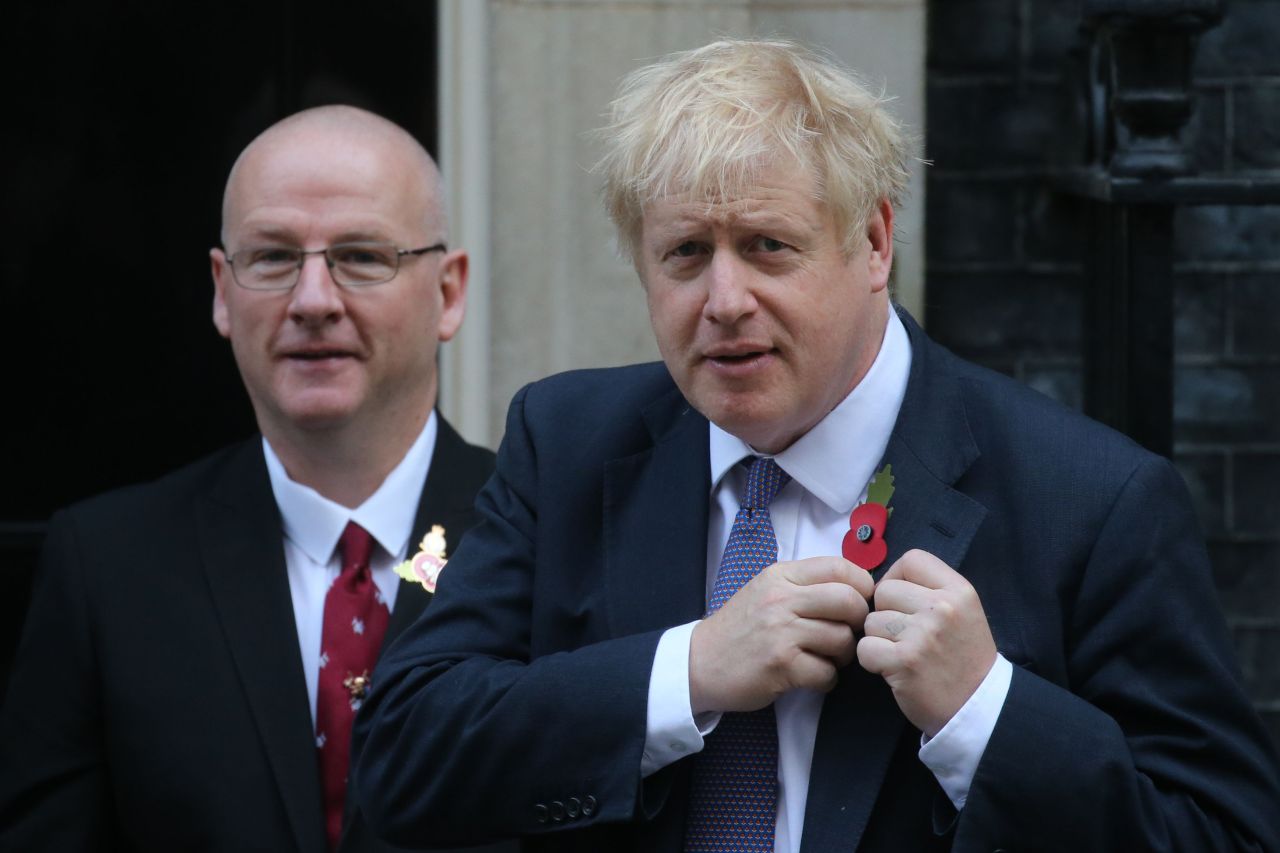 Britain's Prime Minister Boris Johnson (right) pins a poppy to his lapel on the steps of Downing street as he meets with fundraisers for the Royal British Legion in central London on Monday. European Union members agreed Monday to postpone Brexit for up to three months, stepping in with their decision less than 90 hours before Britain was due to crash out with no divorce deal. (AFP)