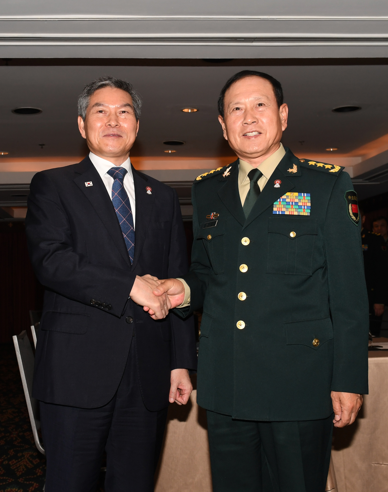 South Korean Defense Minister Jeong Kyeong-doo and his Chinese counterpart, Wei Fenghe hold hands during a bilateral summit on the sidelines of ASEAN Defense Ministers’ Meeting-Plus in Bangkok on Sunday. (Yonhap)
