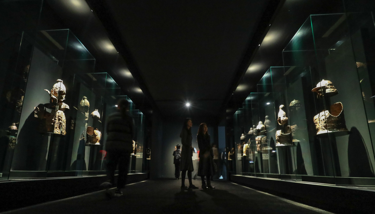 Visitors look at iron armor dating back to the fourth century. (Yonhap)