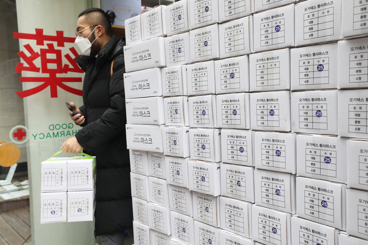 A man leaves a pharmacy in Seoul with boxses of masks on Tuesday.(Yonhap)