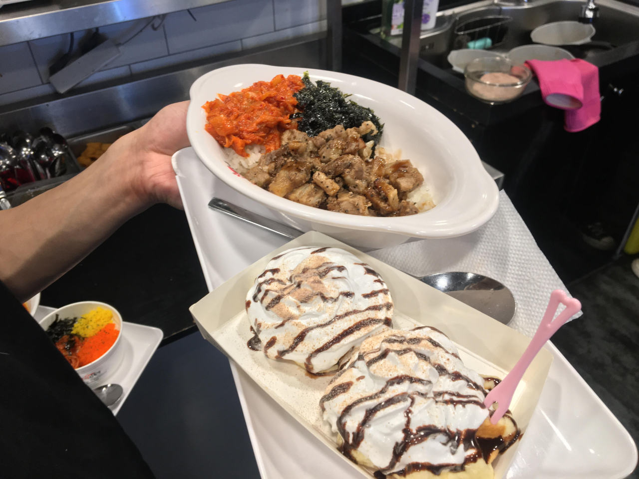 Belgian waffles with whipped cream and chocolate syrup on top and roasted sweet pork belly bowl with fried kimchi. (Kim Byung-wook/The Korea Herald)