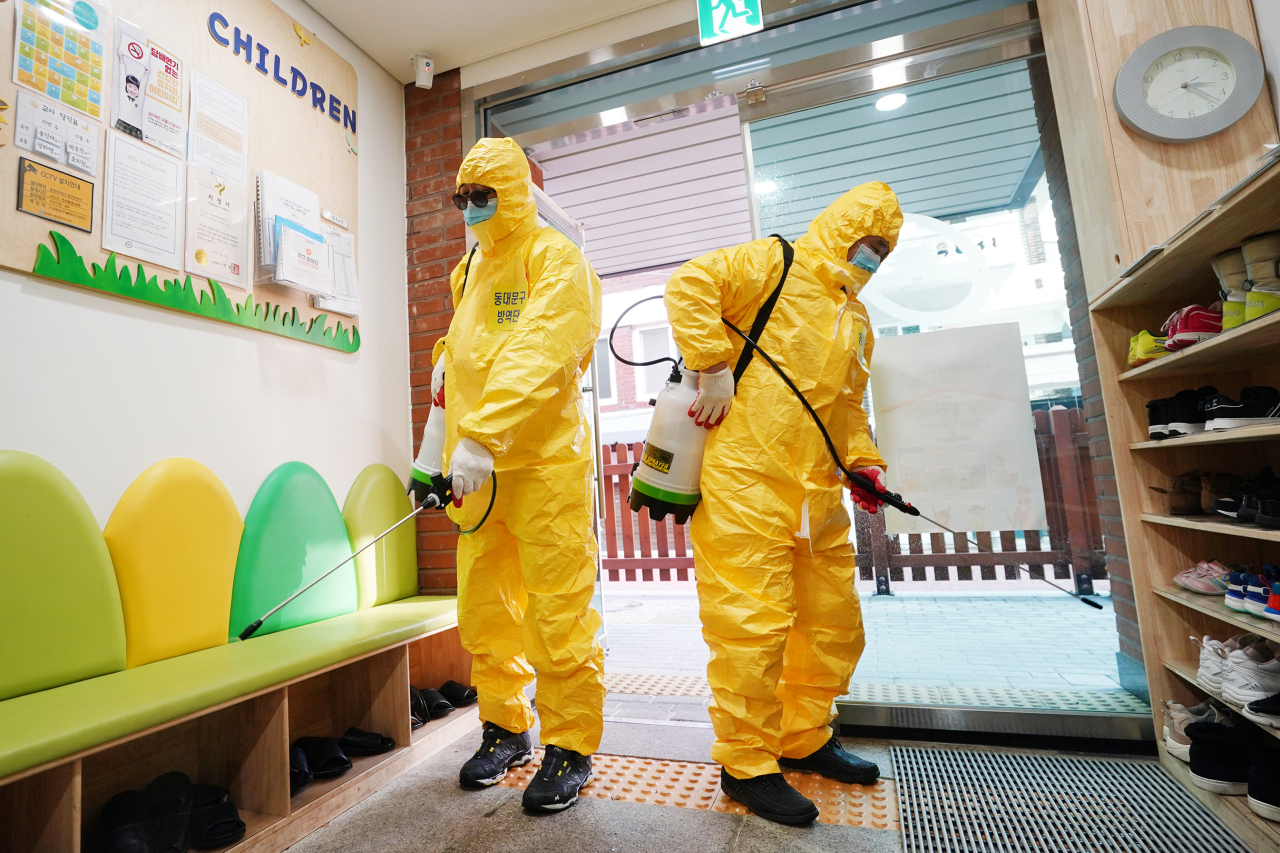 Local volunteers are seen fumigating the entrance to a kindergarten in Dongdaemun, Seoul, Tuesday. (Yonhap)