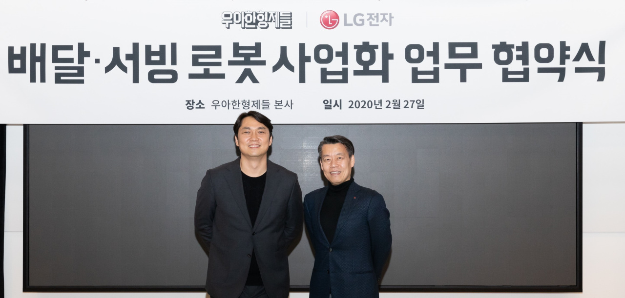 Roh Jin-seo (right), LG Electronics senior vice president and head of the robot business center, and Yoon Hyun-joon, Woowa Brothers vice president of the new business division, sign a memorandum of understanding at Woowa Brothers’ headquarters in Songpa-gu, Seoul, Thursday. (LG Electronics)