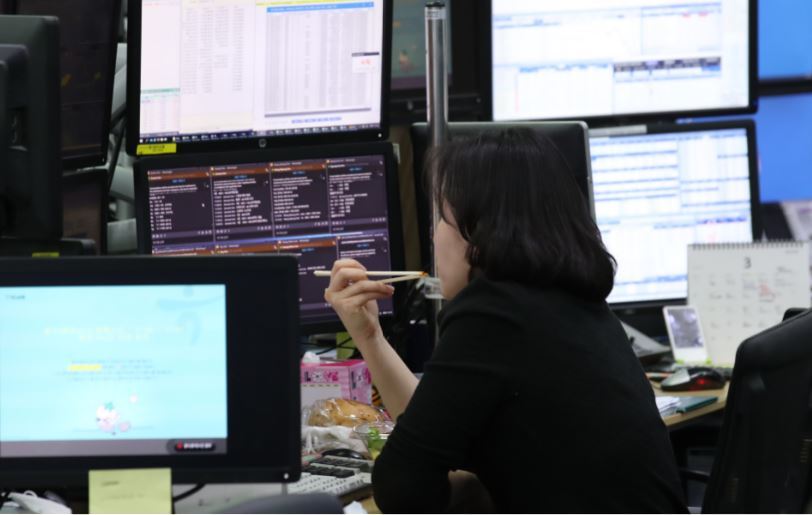 A currency dealer at KEB Hana Bank in Seoul looks at computer monitors during a lunch break on March 13, when the US dollar hovered around 1,218 won and the Kospi plunged to close under 1,800 points. (Yonhap)