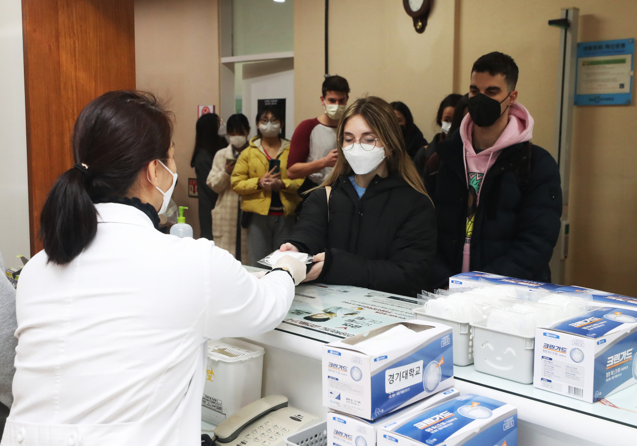 An employee at Kyonggi University in Suwon, Gyeonggi Province, provides foreign students with masks free of charge on Monday. Suwon, the most populous of the province’s 31 cities and counties, reported 20 COVID-19 cases as of Thursday at 10:30 a.m. (Yonhap)