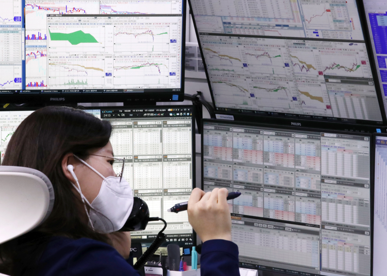 A dealer monitors the movement of the Kospi and foreign exchange trade at KB Kookmin Bank’s dealing room in Seoul on Thursday. (Yonhap)