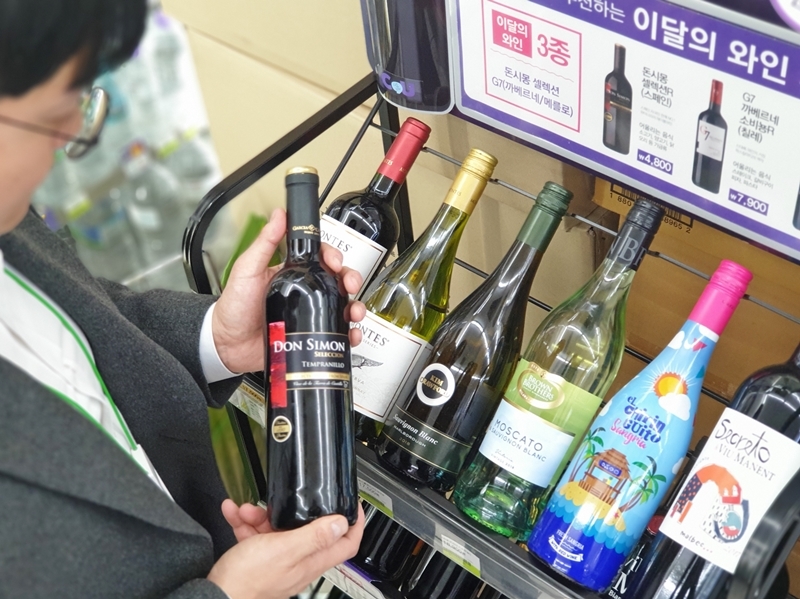 A customer looks at a bottle of wine at a convenience store. (CU)